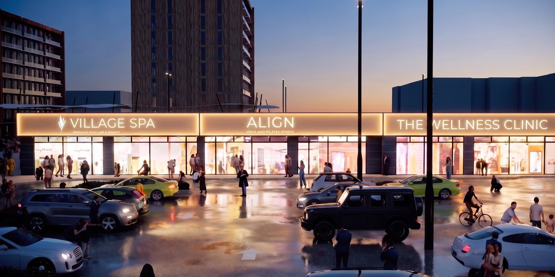 Evening rendering of the Stewart Village plaza with lit storefronts and residential buildings behind